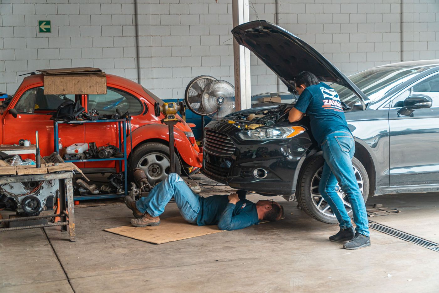 Deux mécaniciens au travail sous et sur une voiture dans l'atelier