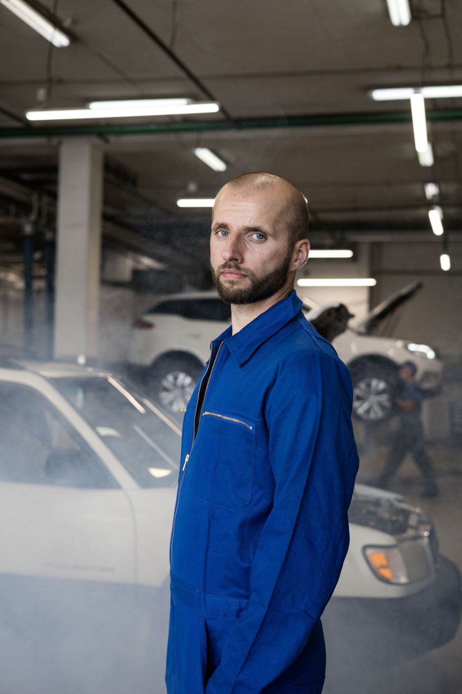 Thomas, gérant du Garage du Centre, en combinaison bleue dans l'atelier